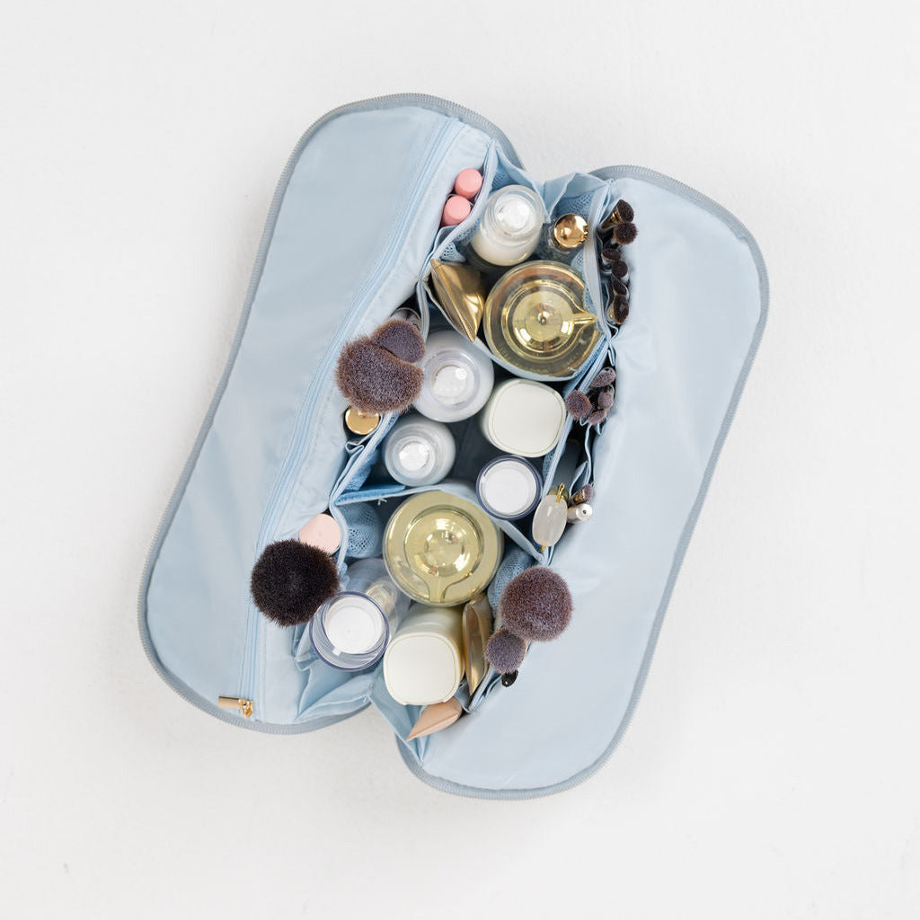 A maroon makeup bag filled with assorted brushes and cosmetics.